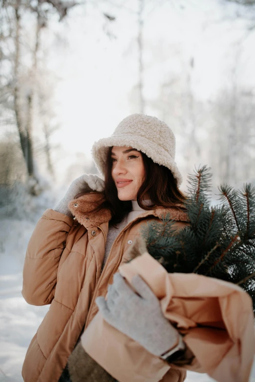 a girl is holding a tree while standing in the snow