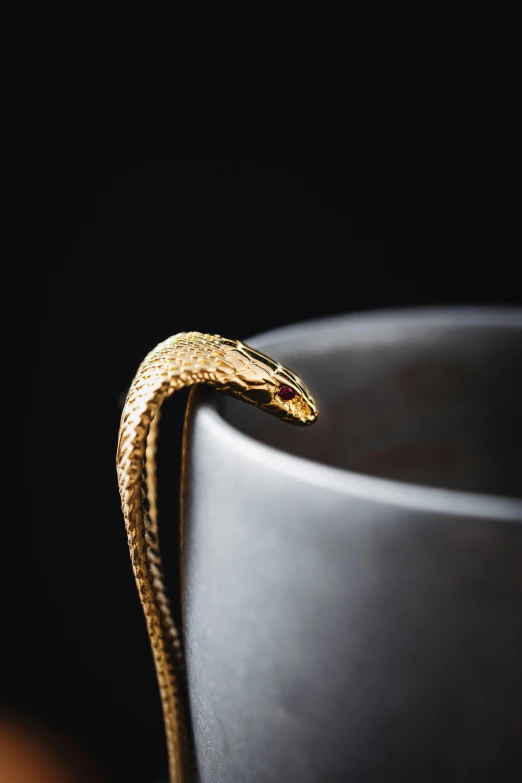 an orange snake sitting on top of a large black vase