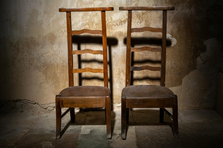 two old wooden chairs with wooden seat cushions