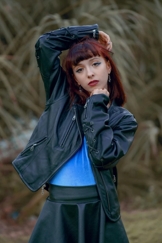 a woman standing in front of trees holding her jacket over her head