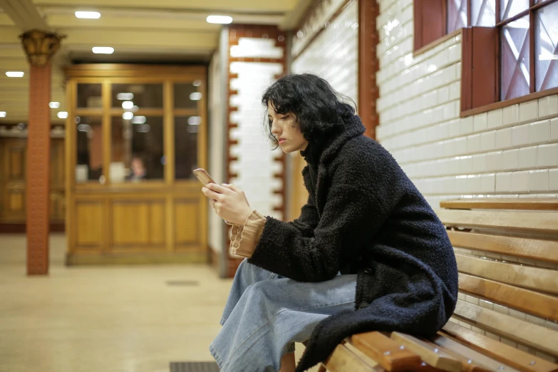 a person sitting on a bench using a cell phone