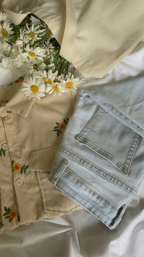 daisy flowers are sitting on a sheet next to light blue jean shorts