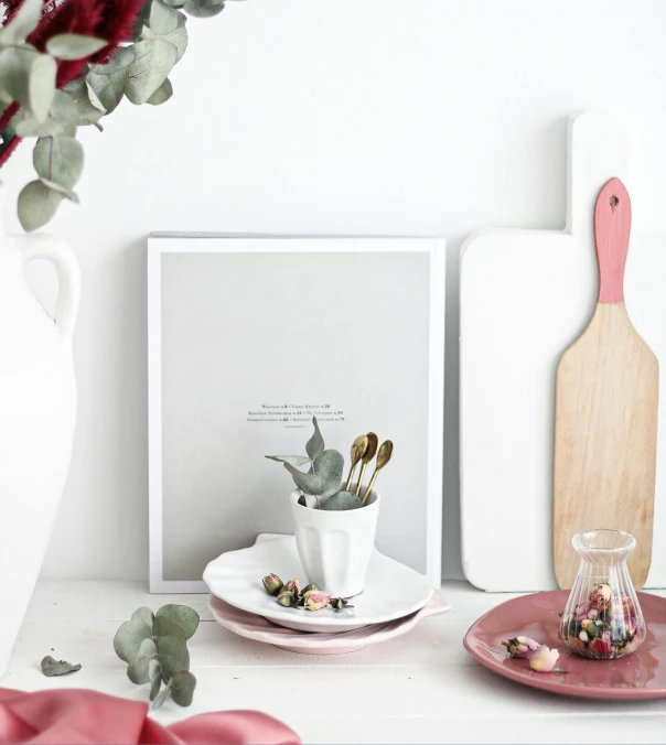 a white and pink kitchen counter with a plate and vase