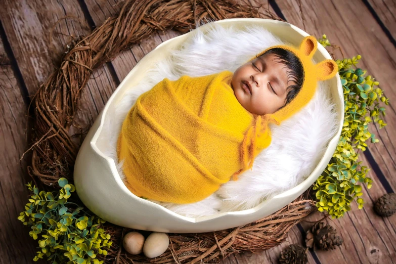 a newborn baby wrapped in yellow on a white surface