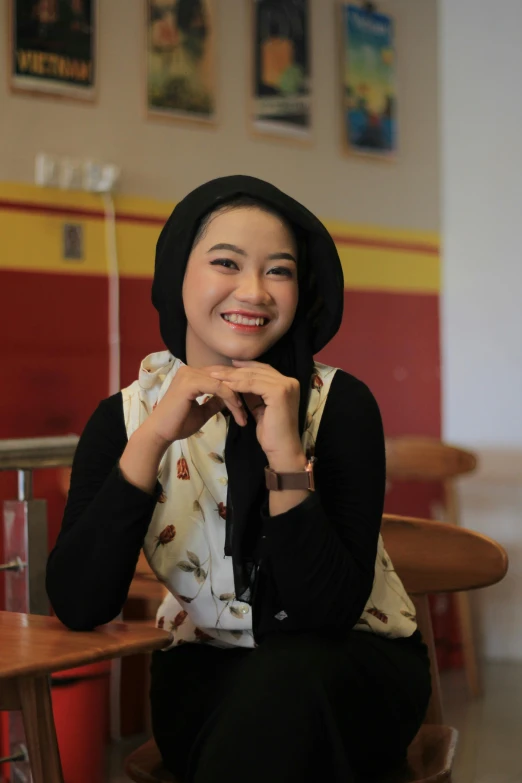 young lady sitting with hands together while smiling