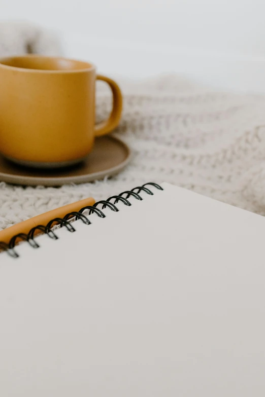 a table with an open notebook and coffee cup