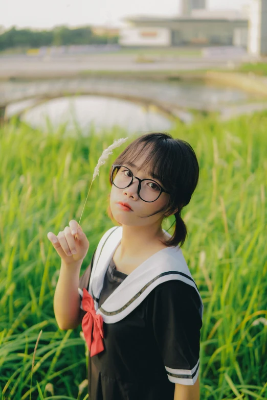 a girl wearing glasses and holding up a flower in her hand