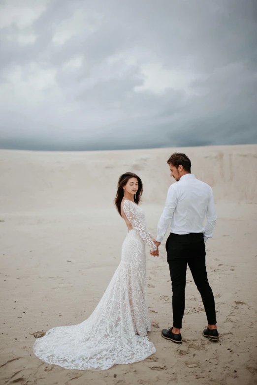 bride and groom standing in front of the sand dunes at a desolate day