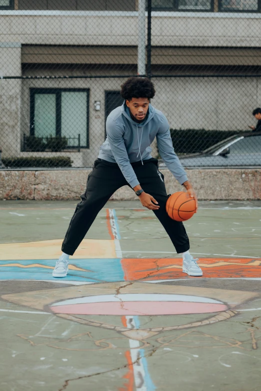 a young man wearing grey and holding a basketball