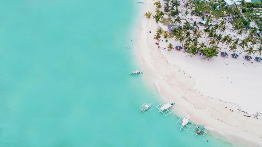 an aerial view of a resort, with white beach and palm trees