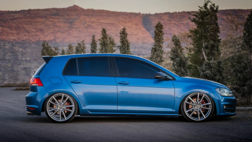 a blue volkswagen is parked in front of mountains