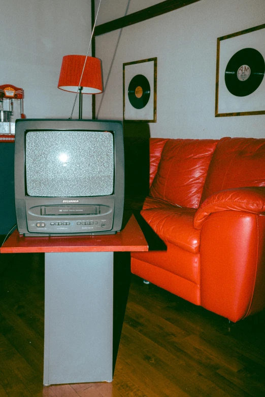 this living room has an old tv and a red couch