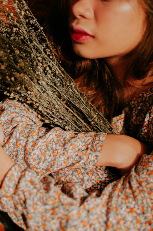 a woman wearing a dress with floral print holding her hands in her arms