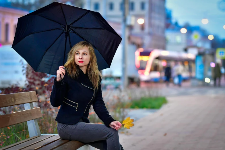 a woman holding an umbrella sits on a bench