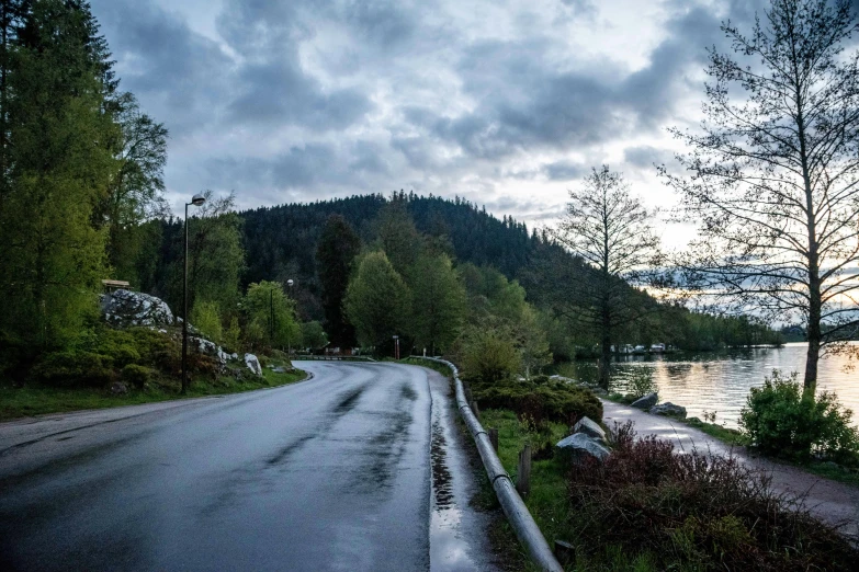 a car drives along the roadside next to the lake