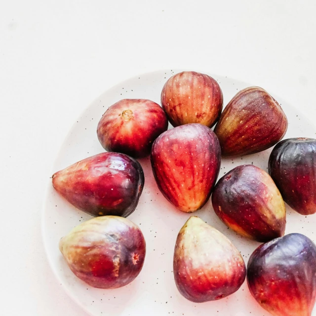 a plate of plums on top of a table