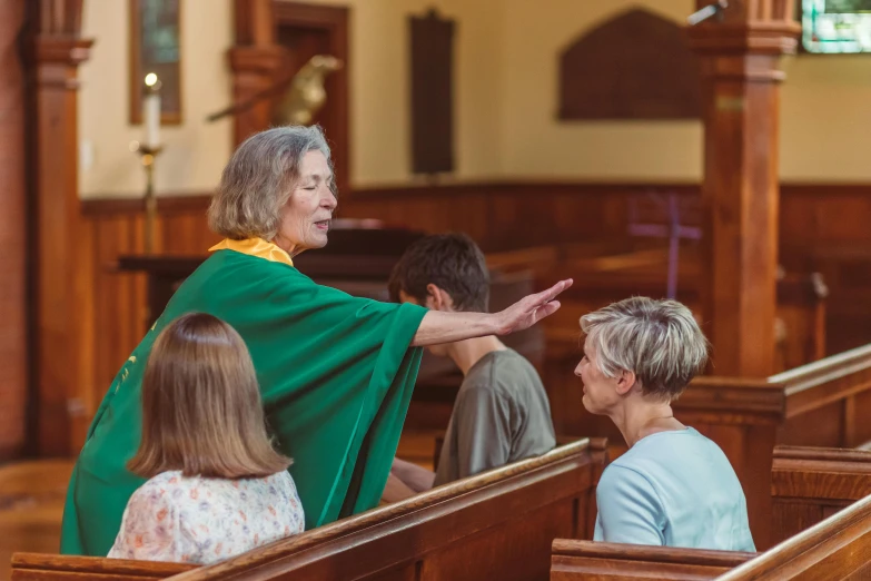 a priest is greeting a woman in a pew