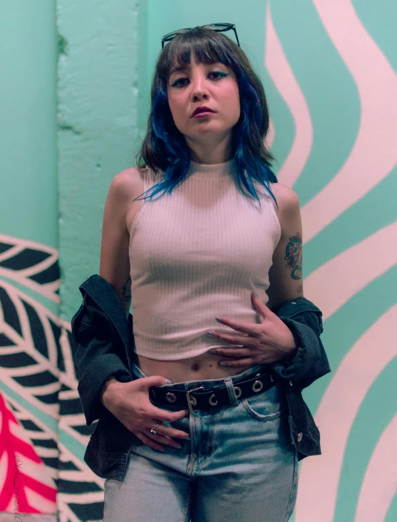 a woman with blue hair and tattoos holding her hand in her pockets