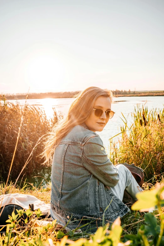 a woman sitting next to some tall grass