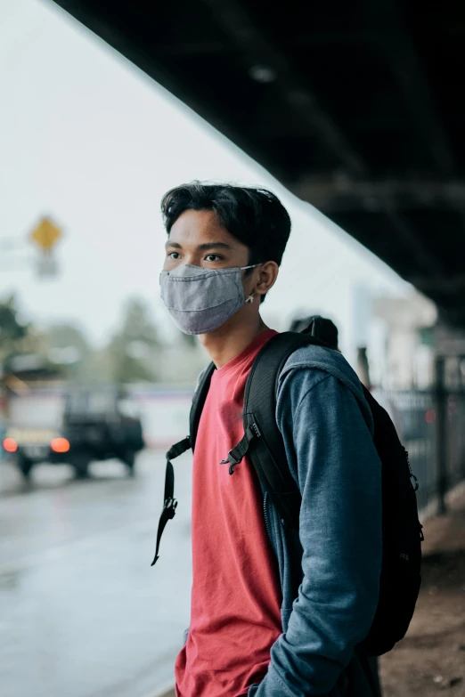 a young man wearing a medical mask with a backpack on