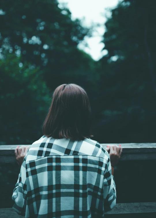 someone standing behind a railing in a park looking off at trees