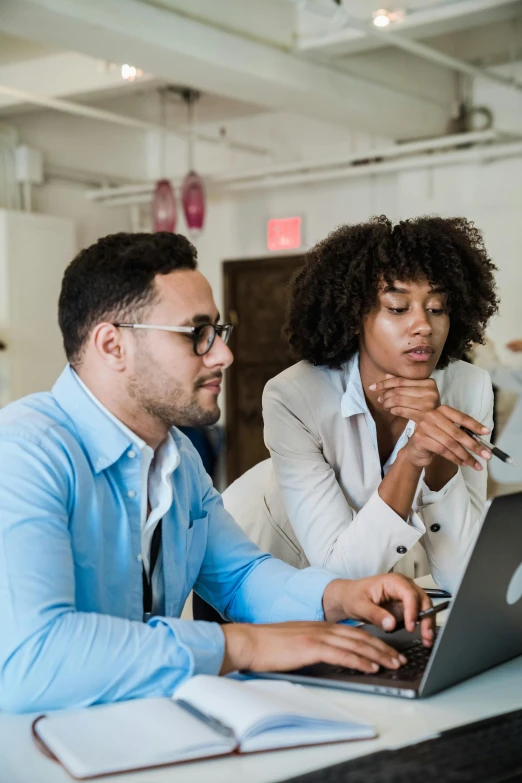 a couple of people sitting in front of a laptop computer