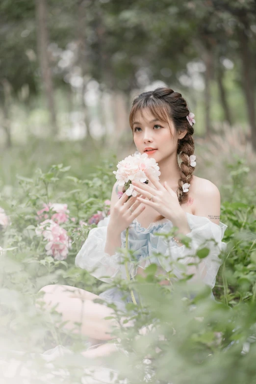 girl in floral dress sitting in a forest holding flowers