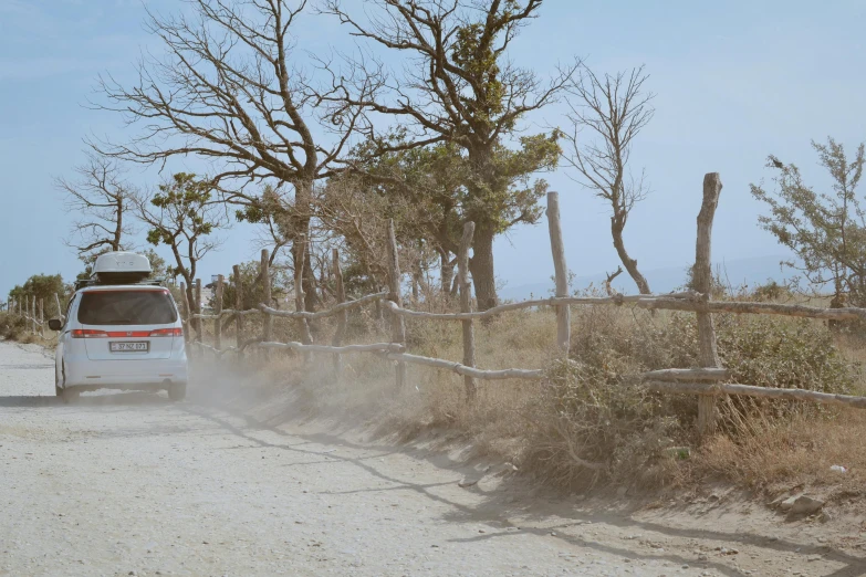 a van drives along a fenced off dirt road