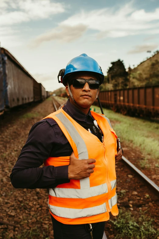 a man standing next to a train with a hat on