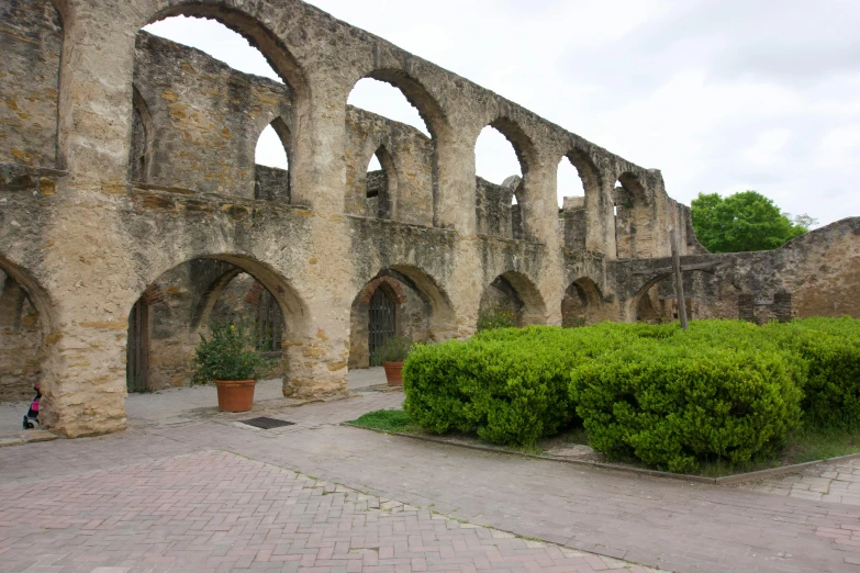 an old building has stone arches and hedges