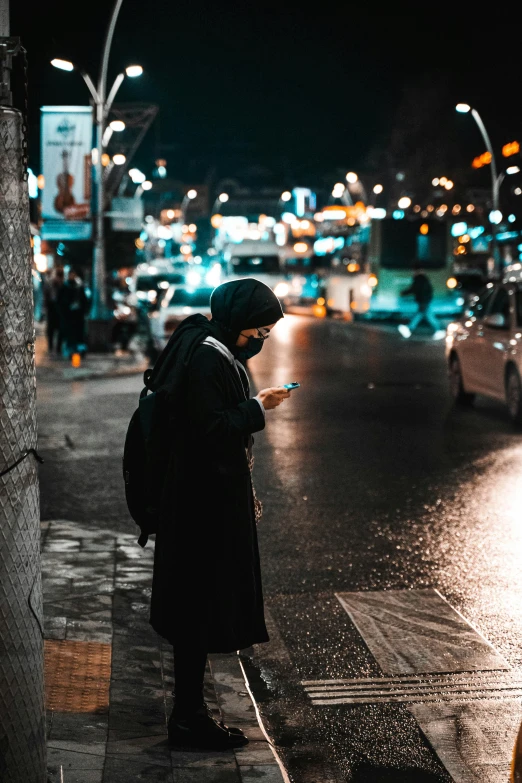 a person is standing on the sidewalk in the rain while checking their phone