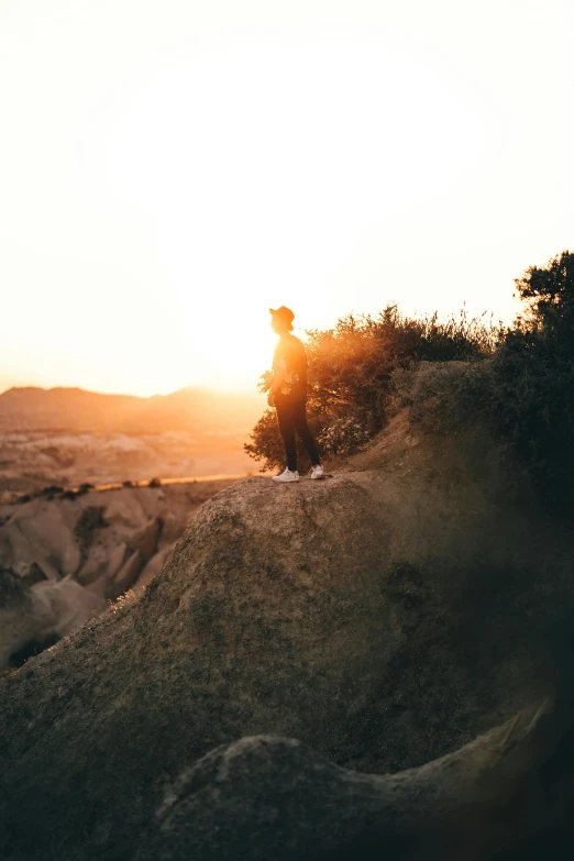 the silhouette of a man sitting on top of a cliff