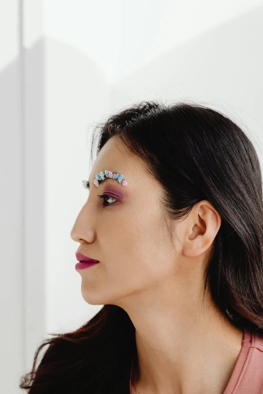 a woman with long hair wearing a colorful pair of false eyeliners