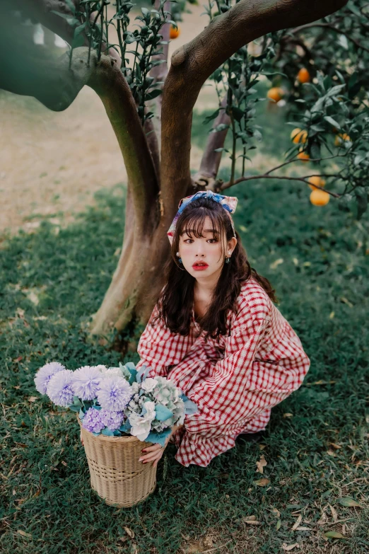 a woman kneeling in front of a tree with some flowers