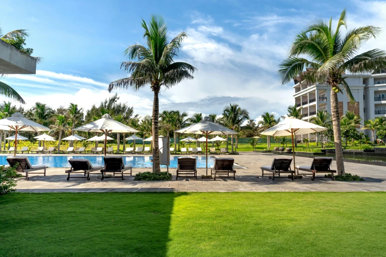 lounge chairs and umbrellas at the back of a resort pool