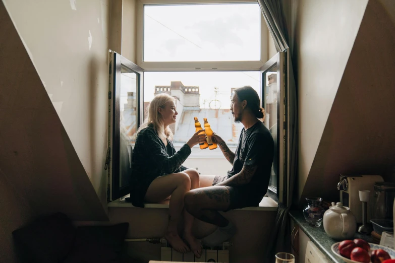 a couple of women sitting on a window sill holding bottles