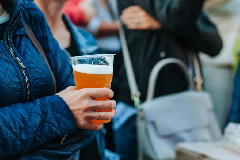 a woman with a beer is standing by a table