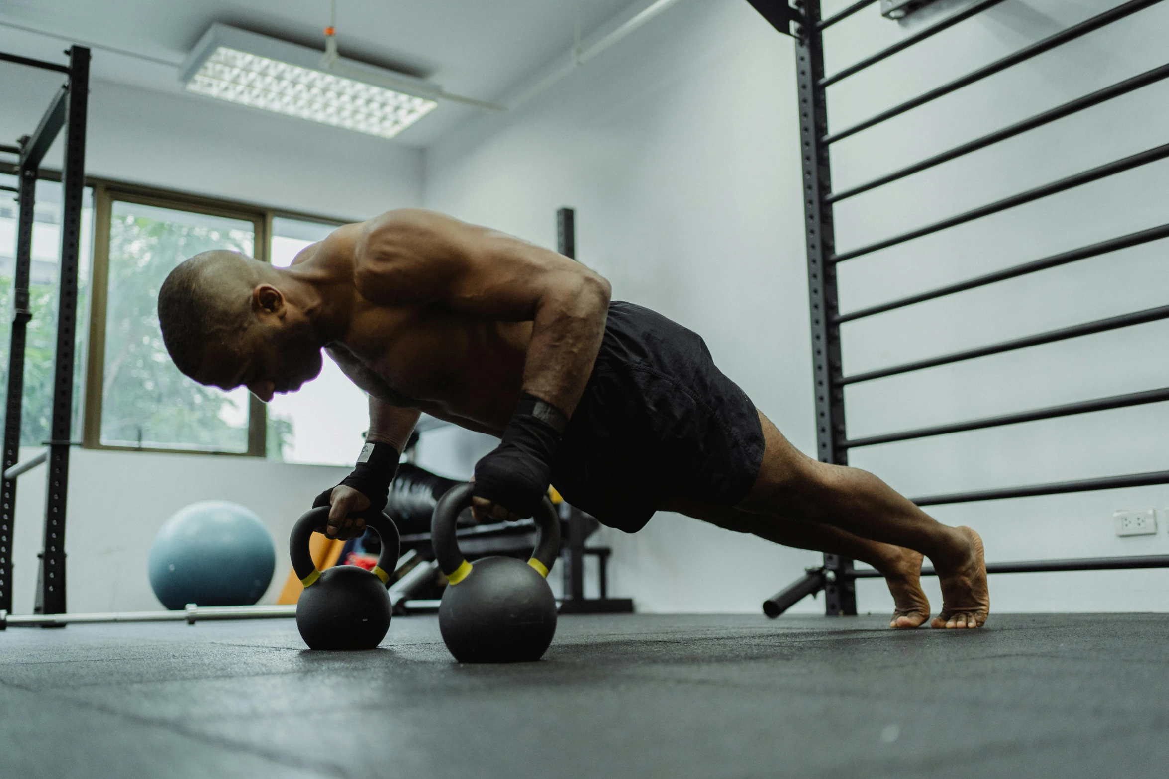 man in gym with dumbbells and a barbell bench