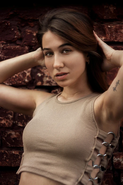 young woman leaning against brick wall wearing an arm tattoo