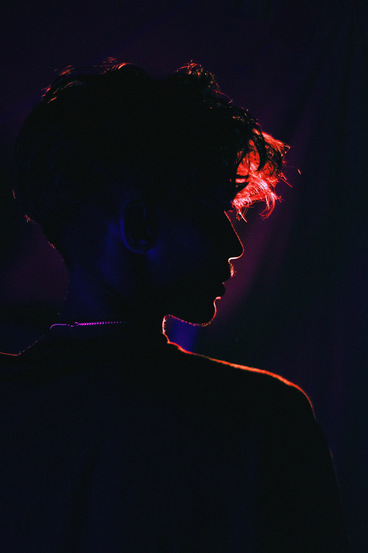 the profile of a young man in front of a neon light