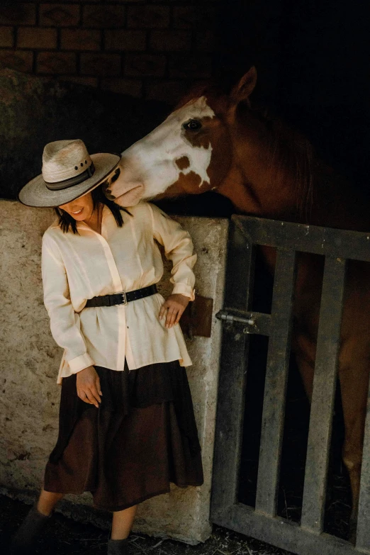 a woman standing beside a horse in the stable