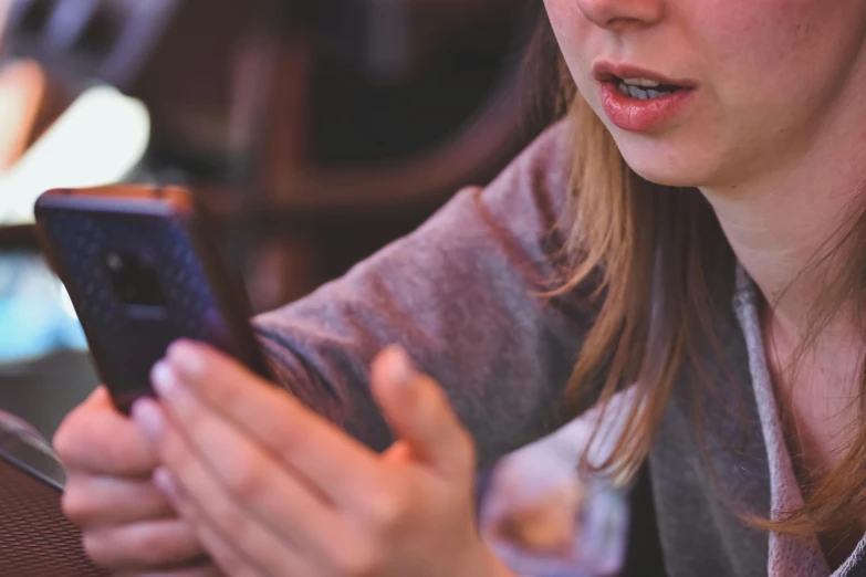 a woman is using her cell phone at the table