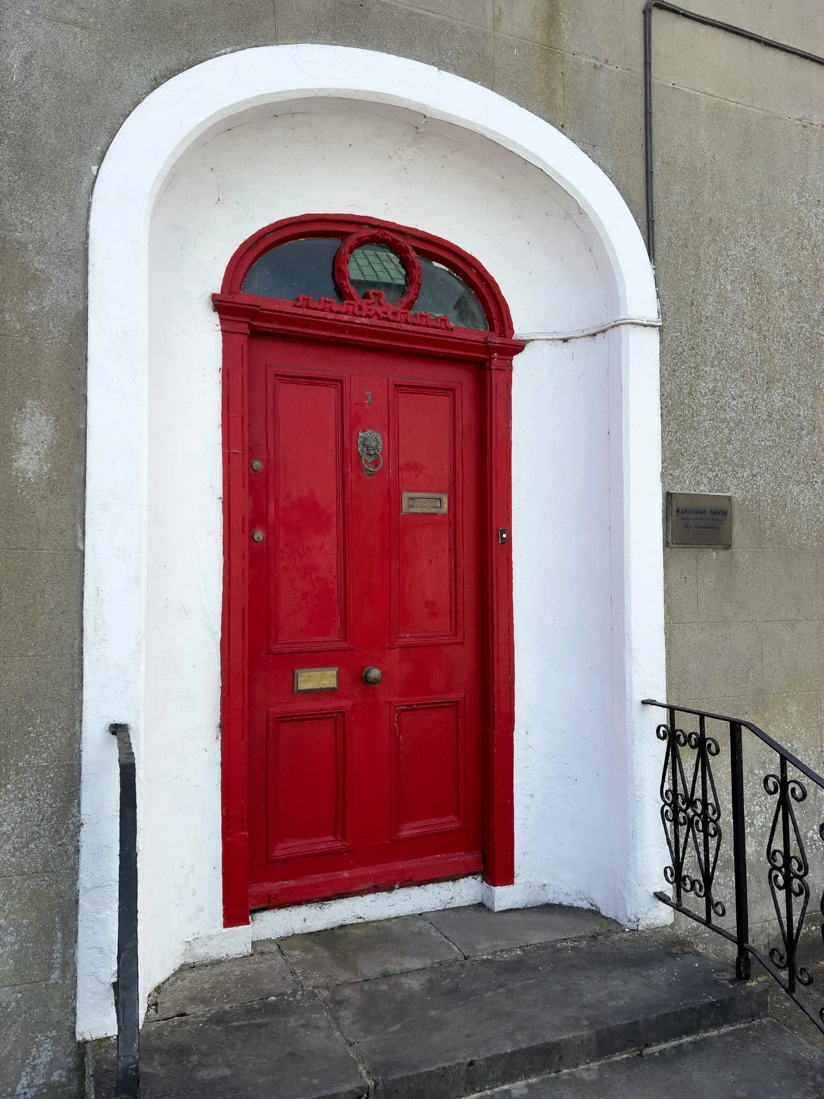 a red door sits on a grey building