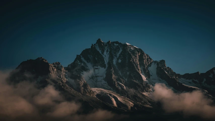 a mountain covered in lots of clouds under a blue sky