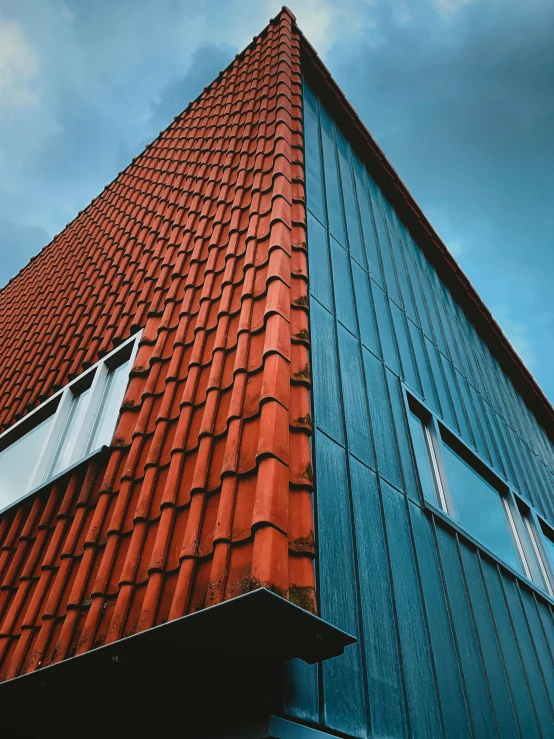 a blue building with red tiles next to a sky background