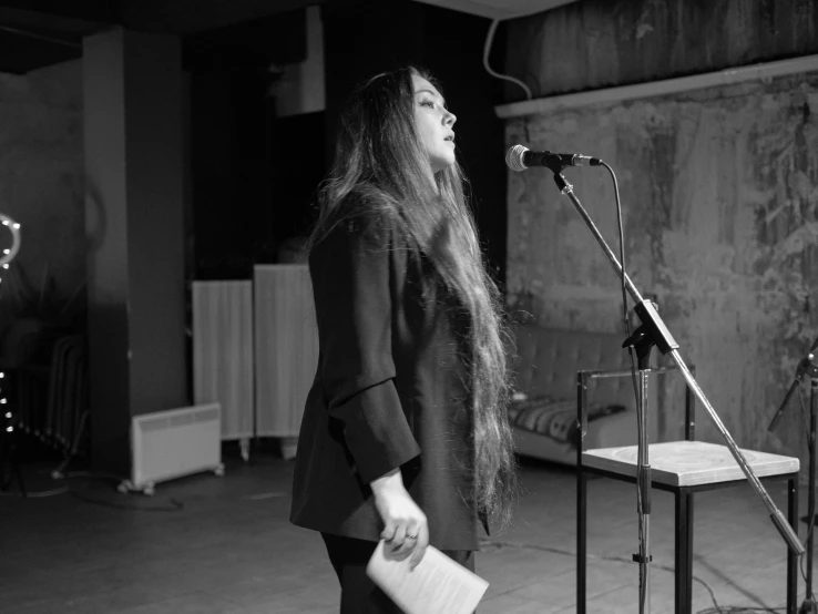 a woman in a coat standing in front of microphone