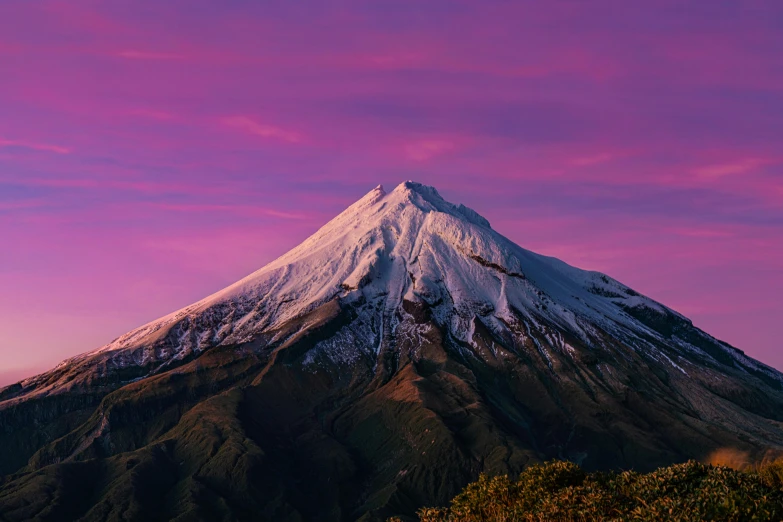 the snow covered mountain rises into the purple sky