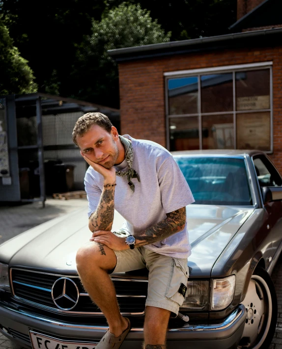 man sitting on hood of mercedes benz