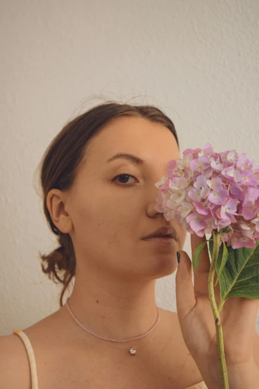 a woman is putting a flower in her face