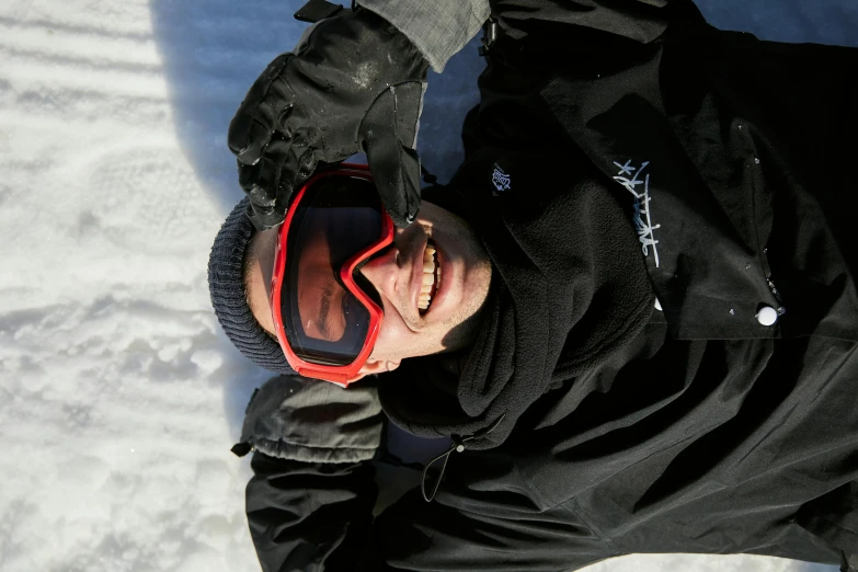 man wearing black jacket and red glasses laying on snow